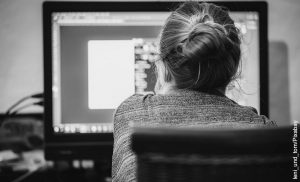 Foto de una mujer frente a su computador que muestra cómo hacer tarjetas de invitación