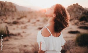 Foto de una mujer con los ojos cerrados respirando al aire libre que ilustra los cortes de cabello