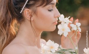 Foto de una mujer oliendo margaritas en el campo que ilustra el significado de las flores