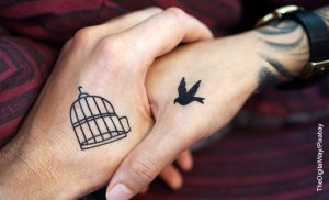 Foto de una pareja tomada de la mano que ilustra los tatuajes de parejas enamoradas