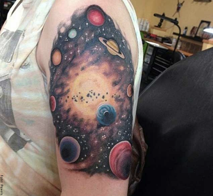 Foto de un tatuaje de planetas y galaxias en el brazo