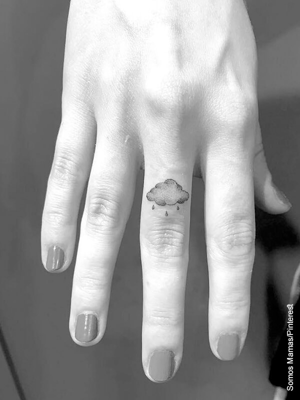 Foto de la mano de una mujer mostrando un tatuaje de nube en uno de sus dedos