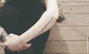 Foto de una mujer sentada con los brazos cruzados que muestran tatuajes para madres