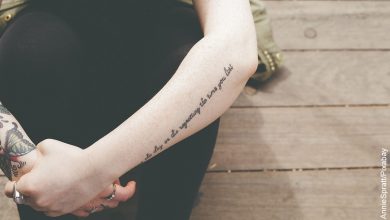 Foto de una mujer sentada con los brazos cruzados que muestran tatuajes para madres
