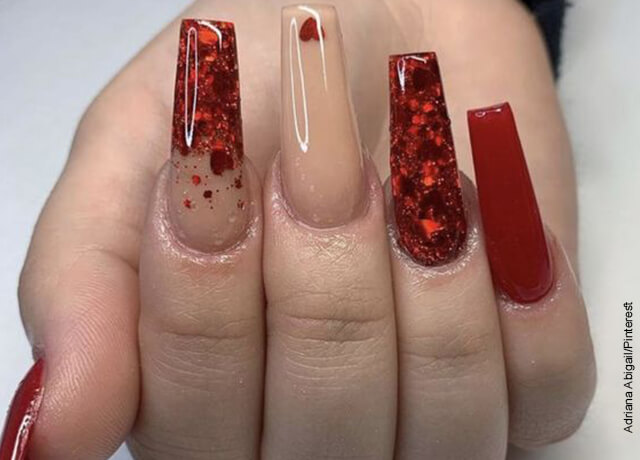 Foto de la mano de una mujer con sus uñas en resina de color rojo