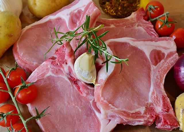 Foto de varios trozos de carne de cerdo junto con cebollas y tomates