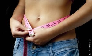 Foto de una mujer midiendo su cintura que muestra cómo reducir el abdomen
