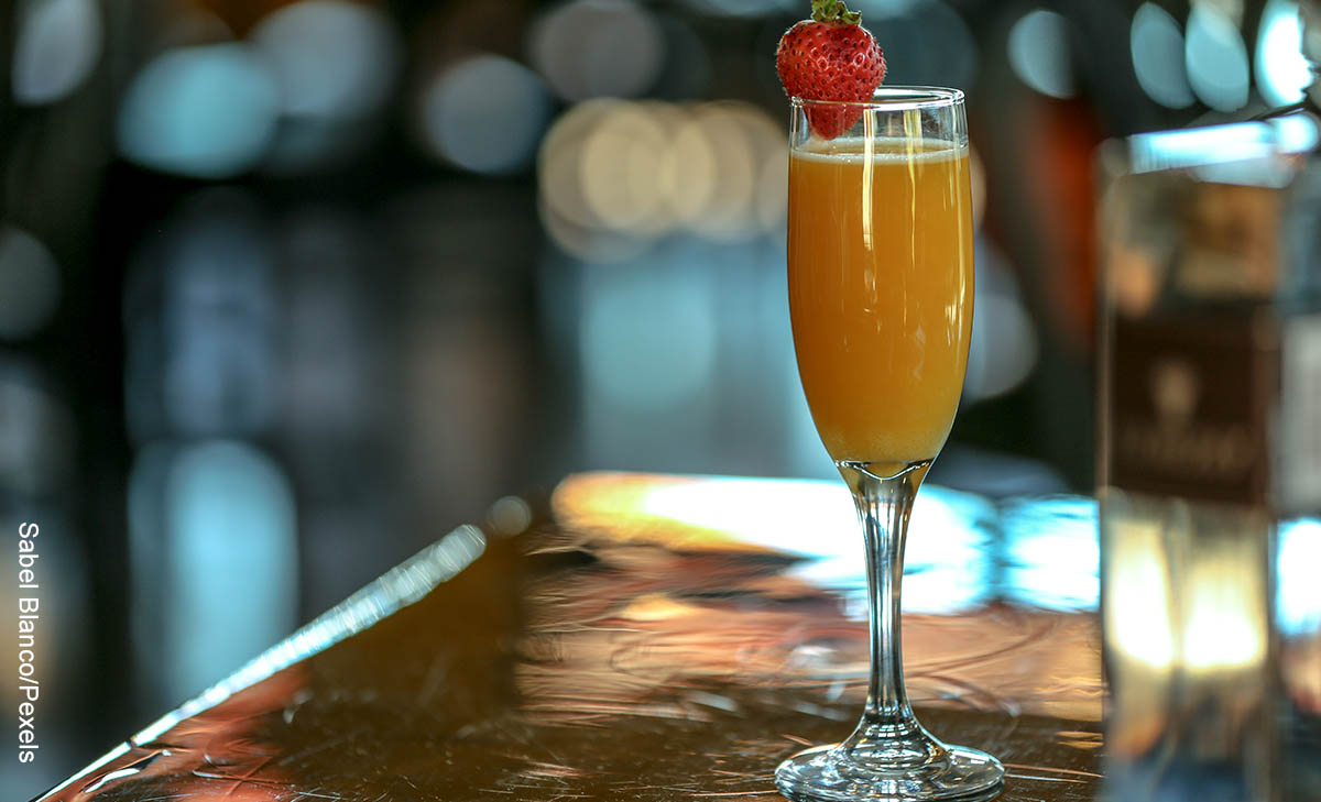 Foto de una copa con una bebida de naranja que muestra cómo hacer mimosa con su receta clásica