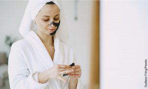Foto de una mujer aplicando una crema en su rostro que ilustra para qué sirve la mascarilla de carbón