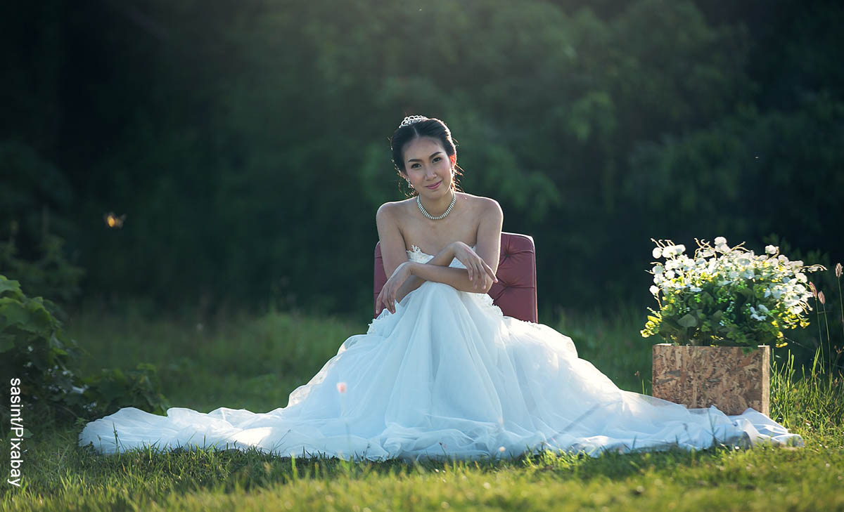 Foto de una mujer sentada en una bosque que ilustra lo que es soñar con vestido de novia