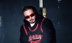 Foto de J Balvin con trenzas y gafas negras y camisa deportiva