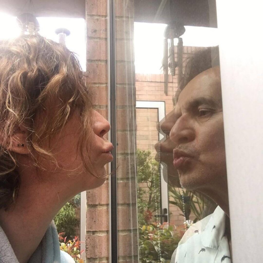 Foto de Jairo Camargo y su esposa besándose a través de un vidrio