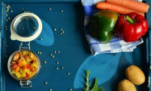 Foto de verduras y papas sobre una mesa azul