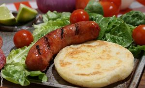 Foto de una arepa con chorizo y ensalada que muestra cómo hacer para que las arepas no queden duras