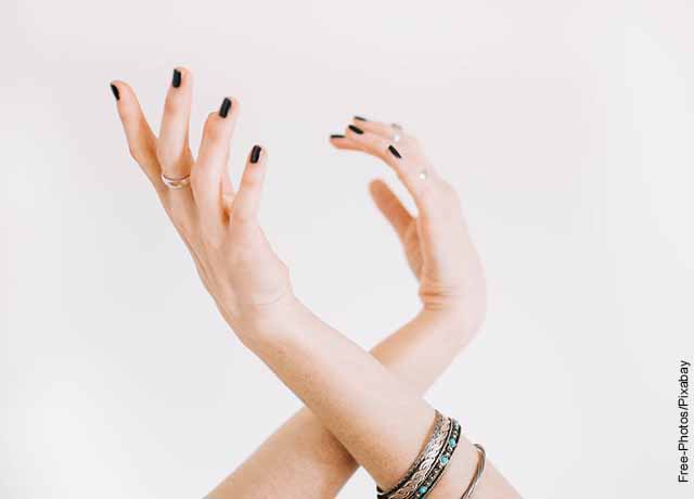 Foto de las manos de una mujer con sus uñas pintadas de negro