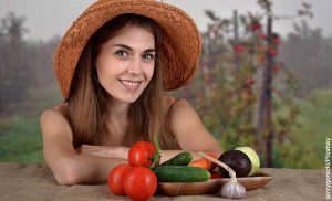 Foto de una mujer con sombrero al lado de algunas verduras que muestra para qué sirve la vitamina A