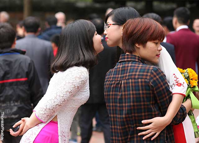 Foto de dos mujeres dándose un beso mientras abrazan a otra