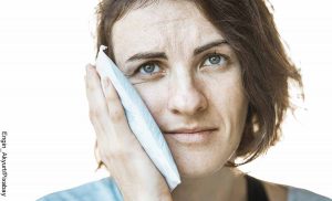 Foto de una mujer poniendo un paño en su cara que muestra qué sirve para el dolor de muela