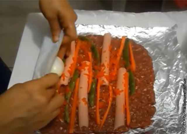 Foto de una persona enrollando carne con verduras