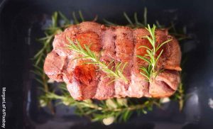 Foto de un rollo de carne con romero en un recipiente que muestra la receta de rollo con carne
