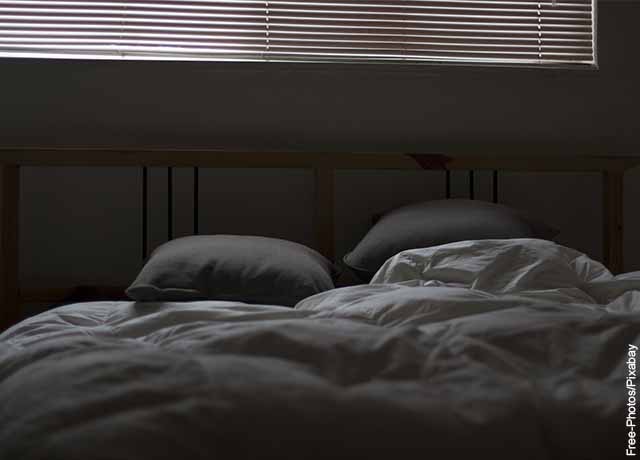 Foto de una cama destendida con dos almohadas que revela lo que es soñar con cama