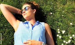 Foto de una mujer recostado en el pasto tomando el sol que muestra para qué sirve la vitamina D