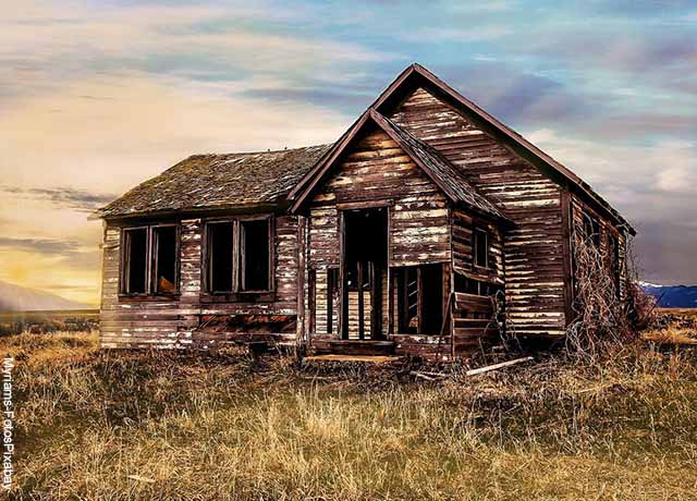 Foto de una casa de madera dañada y vacía que ilustra lo que es soñar con casa