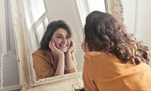 Foto de una mujer mirándose al espejo mientras sonríe que muestra el ácido salicílico para qué sirve