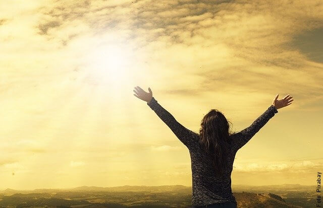 Foto de una mujer libre y tranquila con los brazos abiertos hacia el cielo