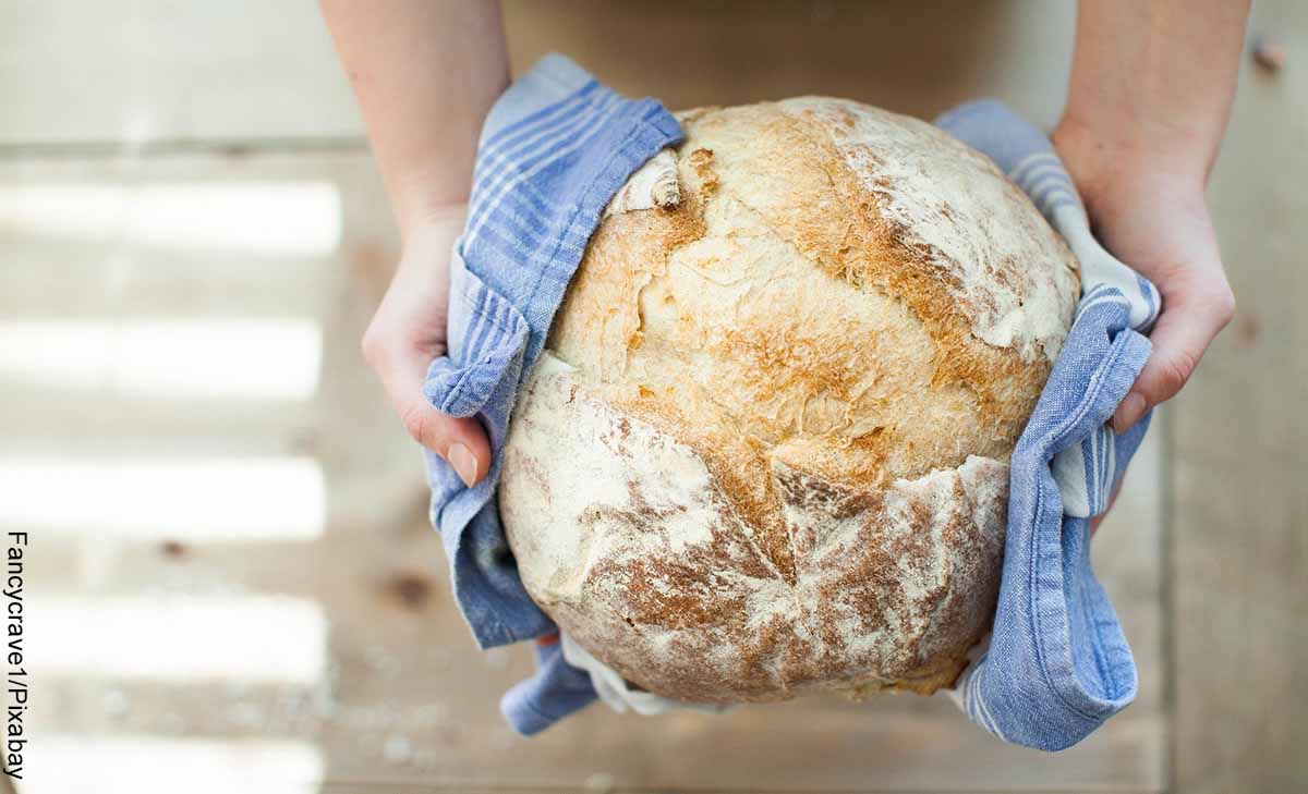 Foto de una persona sosteniendo una masa horneada que revela cómo hacer pan casero