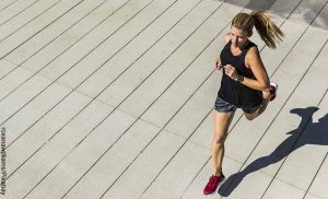 Foto de una mujer corriendo por una vía que revela la glutamina para qué sirve