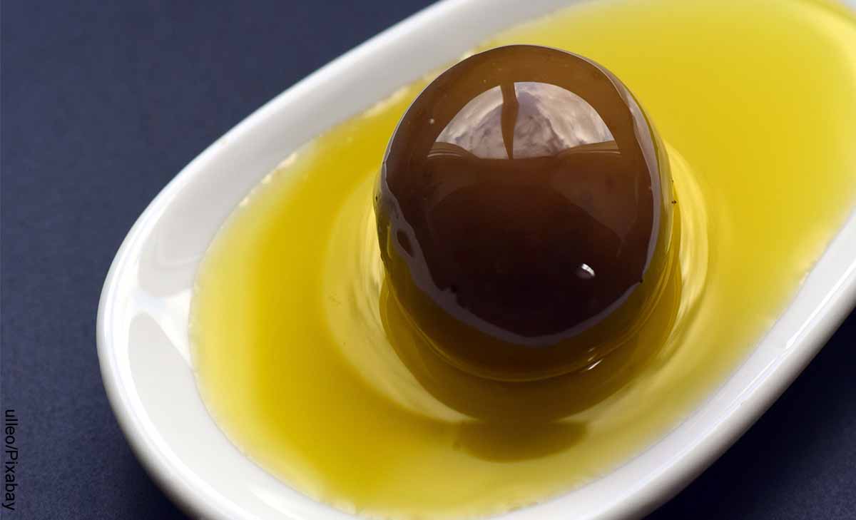 Foto de un olivo y aceite en una cuchara que muestra para qué sirve el aceite de oliva con limón