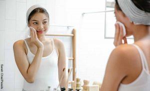 Foto de una mujer limpiando su rostro con un pomo que ilustra para qué sirve la vitamina E en la cara