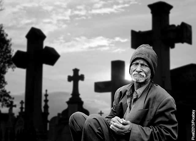 Foto de un anciano sentado en un cementerio