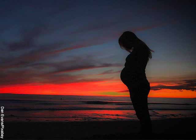 Foto de una mujer embarazada en la playa al atardecer