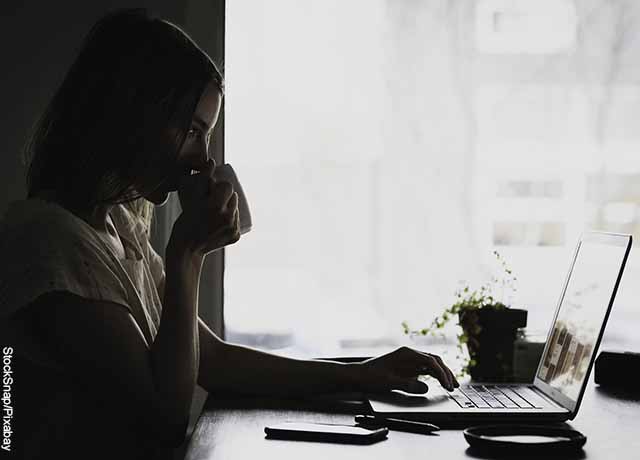 Foto de una mujer sentada en un escritorio tomando café que revela lo que es soñar con trabajo