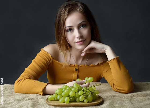 Foto de una mujer comiendo uvas verdes que revela lo que significa soñar con uvas