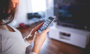 Foto de una mujer sosteniendo su celular en las manos que muestra las aplicaciones para ver películas gratis
