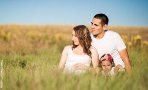 Foto de padres con su hija sentados en el campo que revela las canciones para dedicar a un hijo