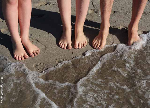 Foto de los pies de personas a la orilla del mar