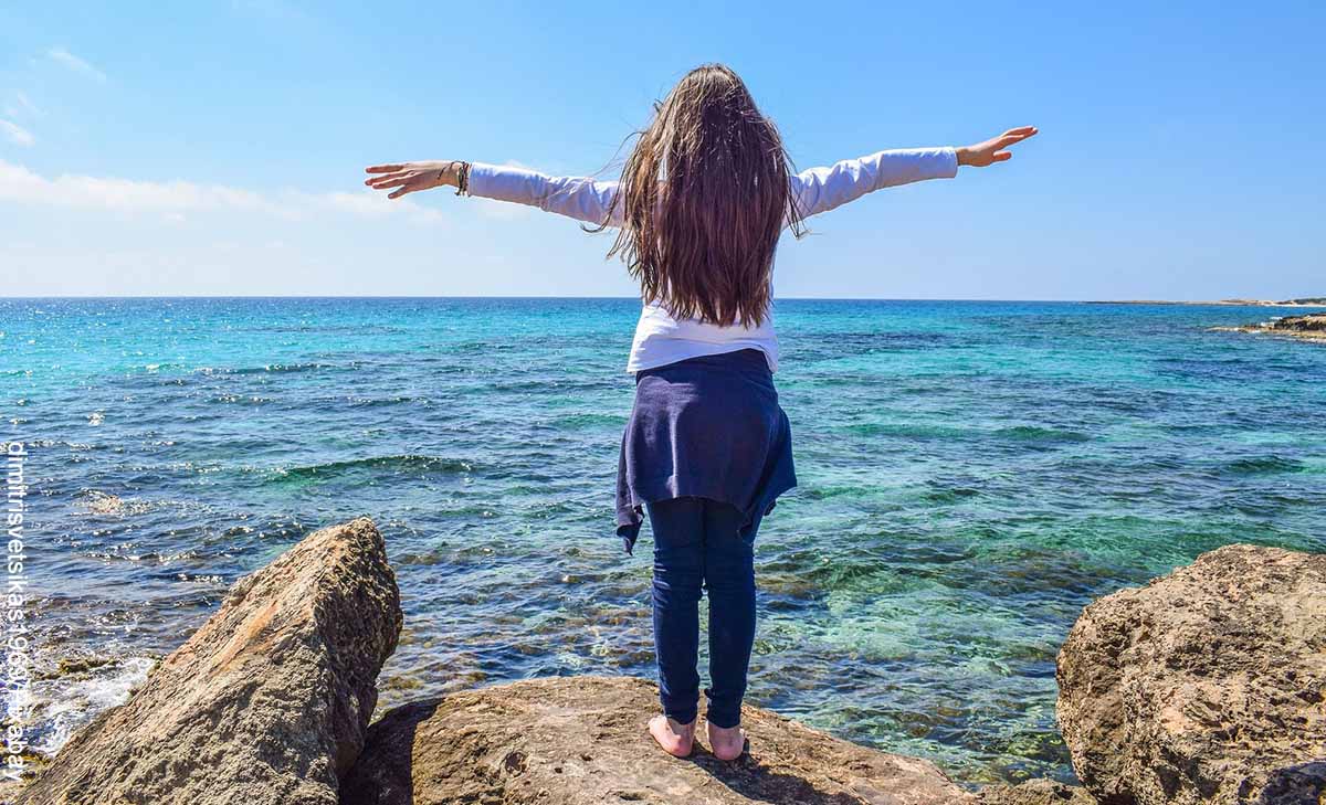 Foto de una niña parada sobre una roca frente al mar que revela qué es la dimensión espiritual