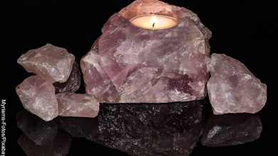 Foto de una piedra mineral rosada con una vela que muestra el significado de los cuarzos