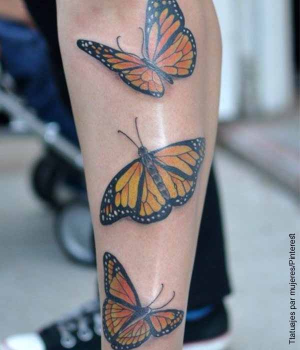 Foto de tres mariposas cafés tatuadas en una pierna