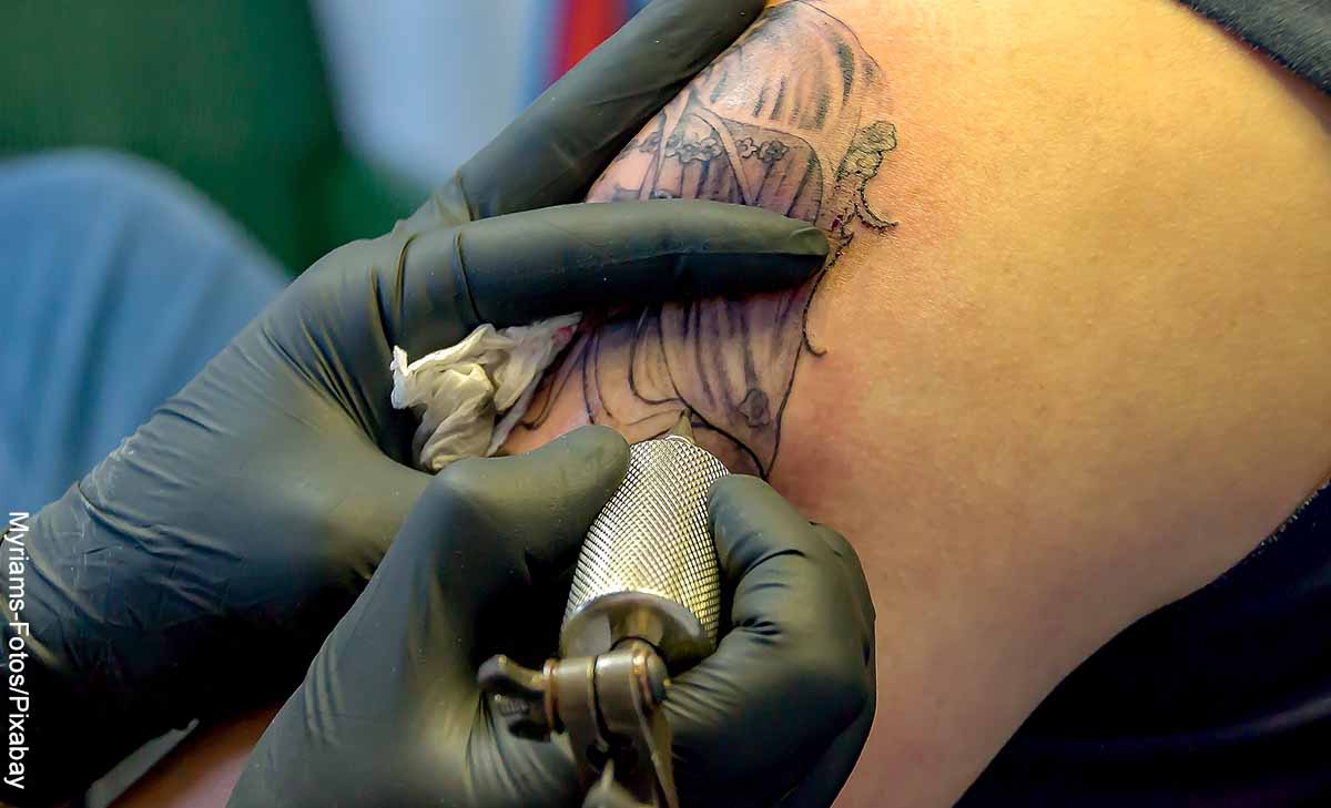 Foto de un tatuador dibujando sobre la piel que revela los tatuajes de mariposas y su significado