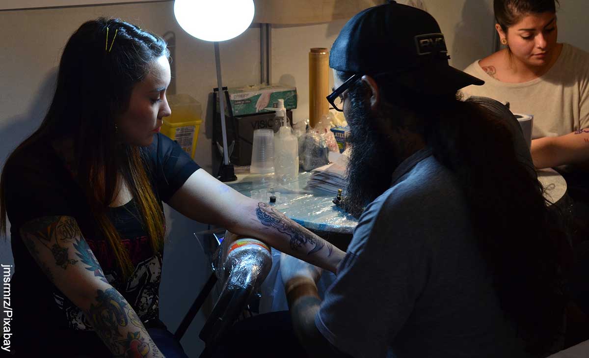 Foto de un tatuador haciendo un diseño que revela los tatuajes de relojes y su significado