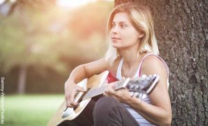 Foto de una mujer tocando la guitarra que revela las canciones para dedicar a alguien que me gusta