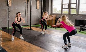 Foto de tres mujeres haciendo ejercicio que revela cómo hacer sentadillas
