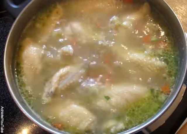 Foto de una olla con vegetales, pollo y agua hirviendo