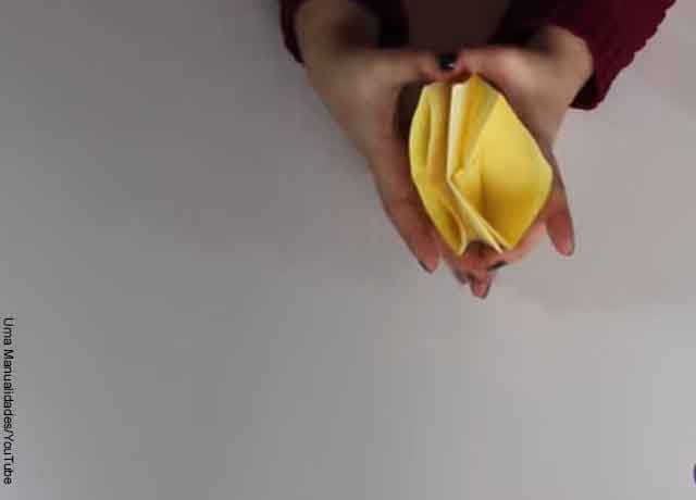 Foto de unas manos con un papel plegado que revela cómo hacer un títere de papel