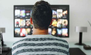 Foto de un hombre sentado frente a su tv que muestra las mejores películas de todos los tiempos